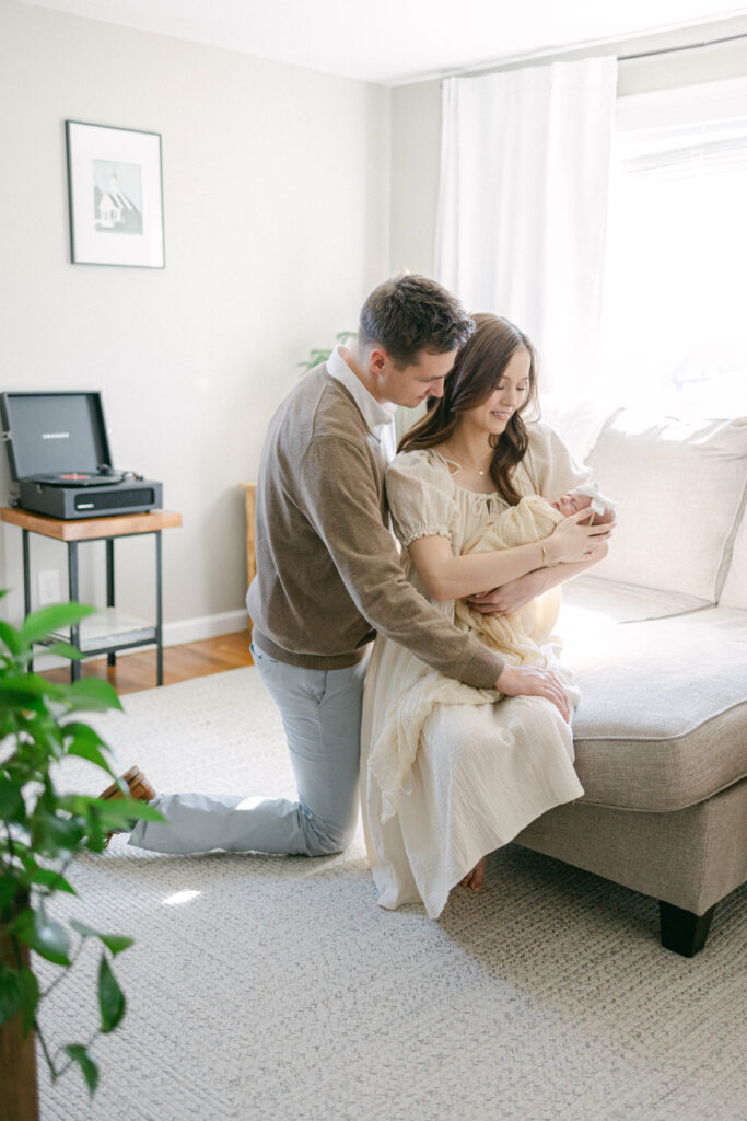 knoxville newborn photographer. man and women sitting holding new baby. lots of window light and creamy tones