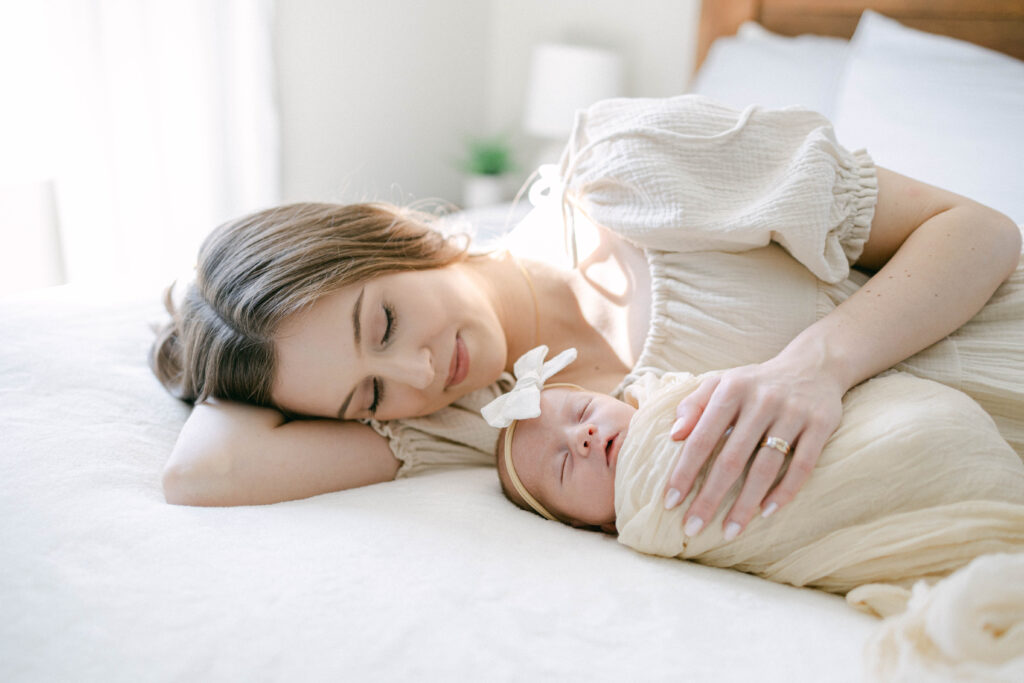 knoxville newborn photographer. mom laying on her side with swaddled newborn laying next to her. creamy neutral tones