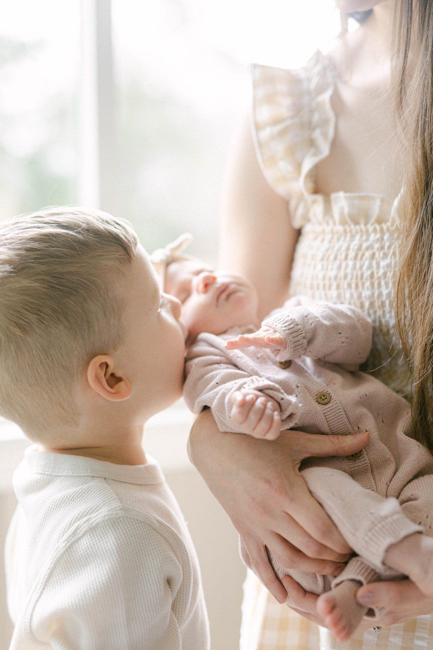 toddler boy kissing newborn sister in moms arms. bright and natural light. knoxville newborn photographer