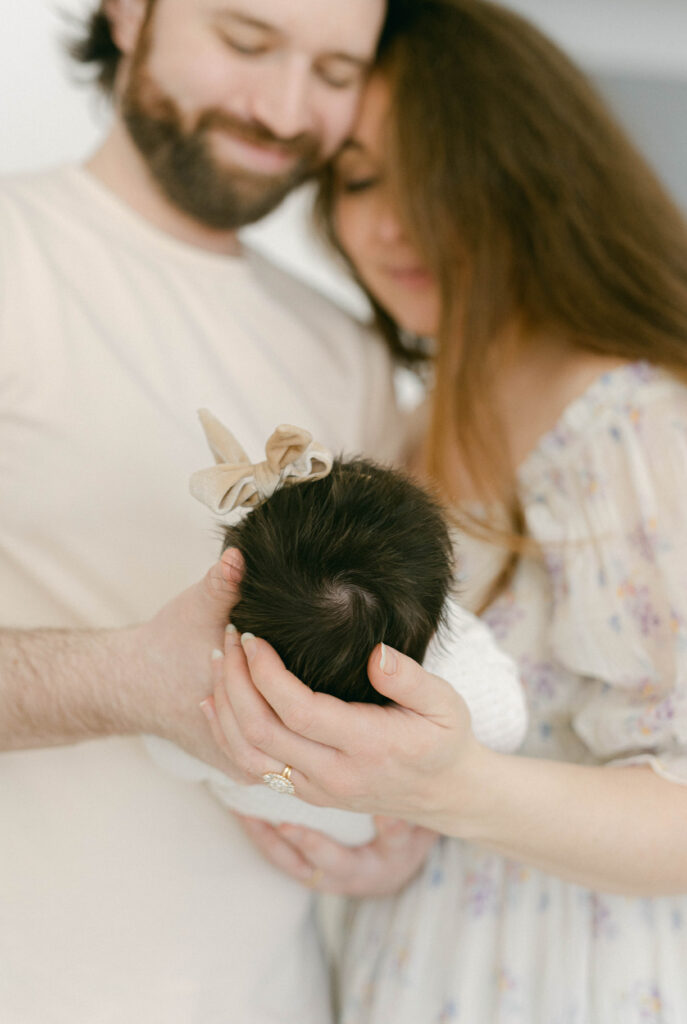 knoxville newborn photographer. mom and dad holding baby in background while focus is on baby's head