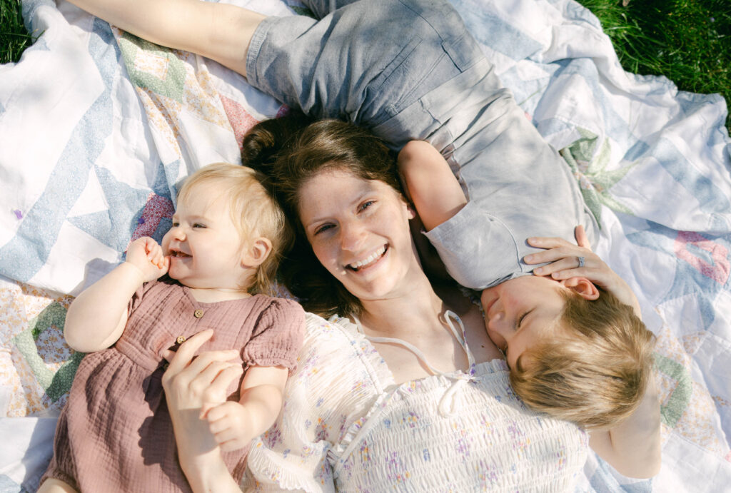  lifestyle session of mom laying on colored quilt laughing with her kids in bright son
