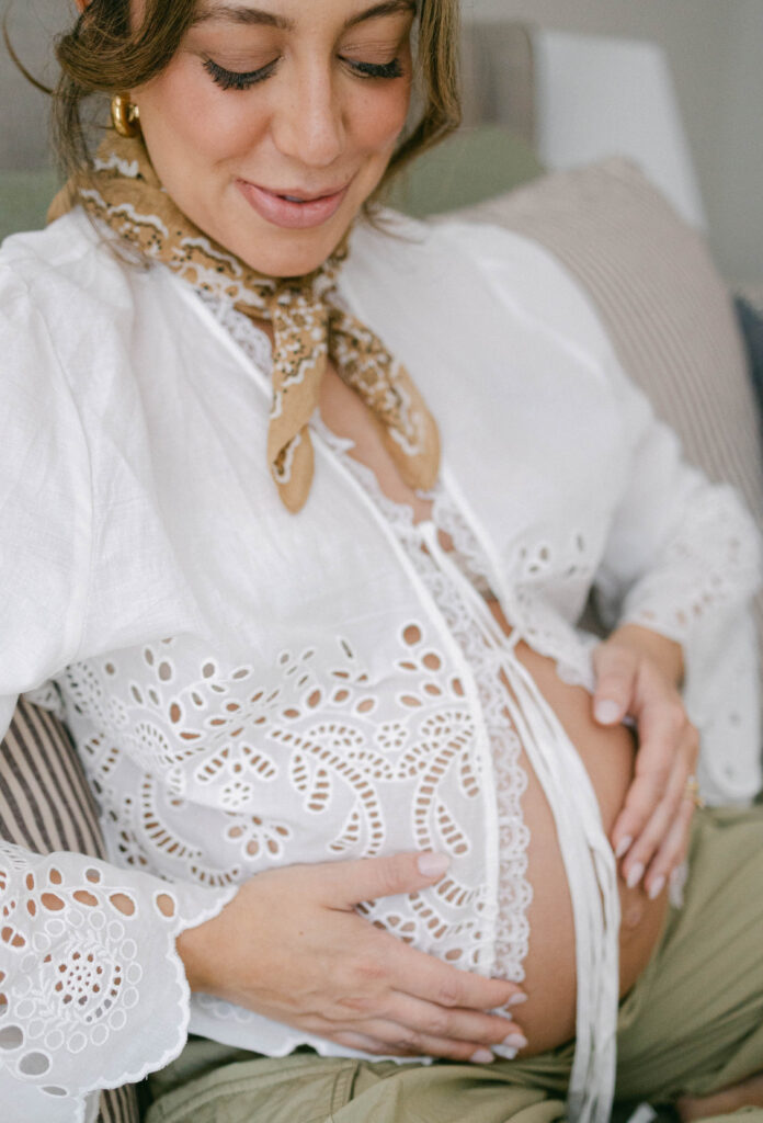 Mom-to-be smiling as she cradles her baby bump during an intimate in-home maternity session.
