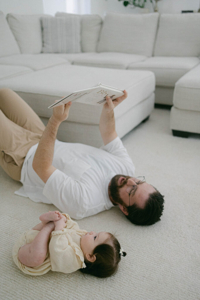 Dad and little girl together on the living room floor reading during a relaxed in-home family photography session in Knoxville