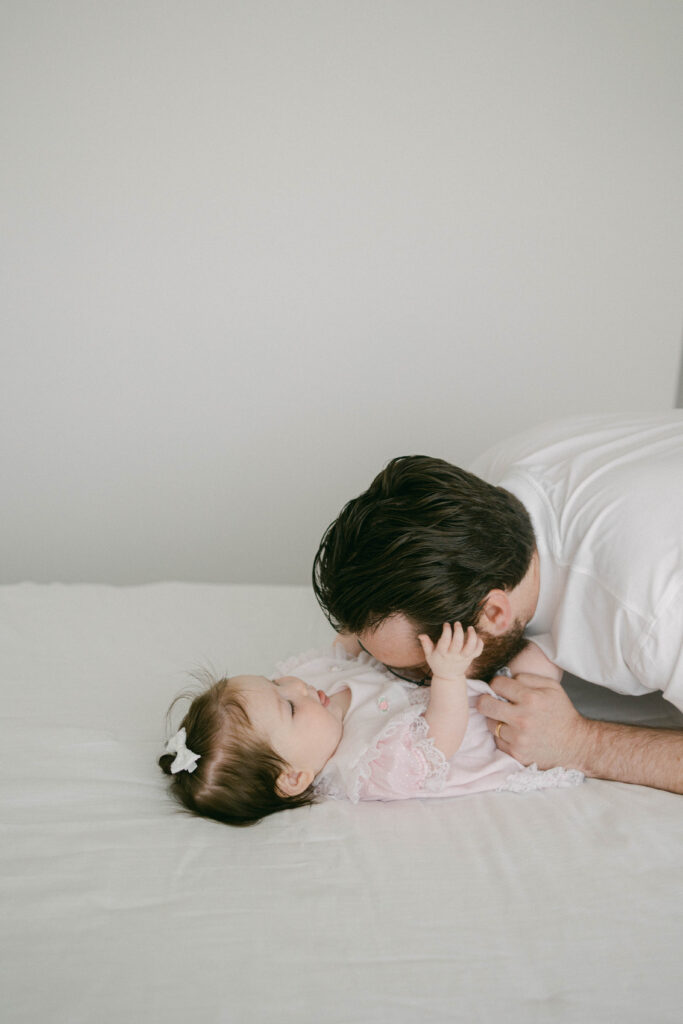 Dad cuddling little girl on bed during Knoxville milestone session